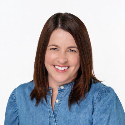 Smiling woman with shoulder-length brown hair wearing a blue shirt.