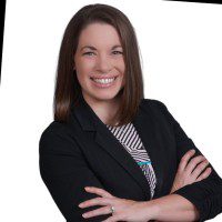 Professional woman smiling confidently with arms crossed in business attire.