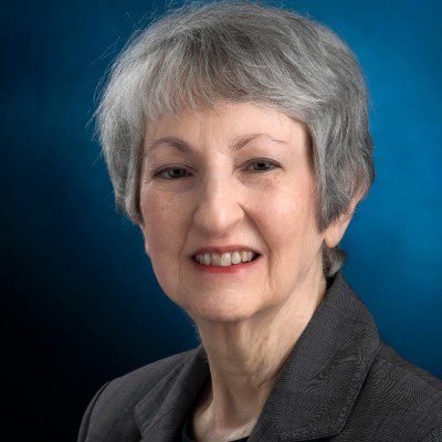 Professional portrait of a smiling older woman with gray hair.